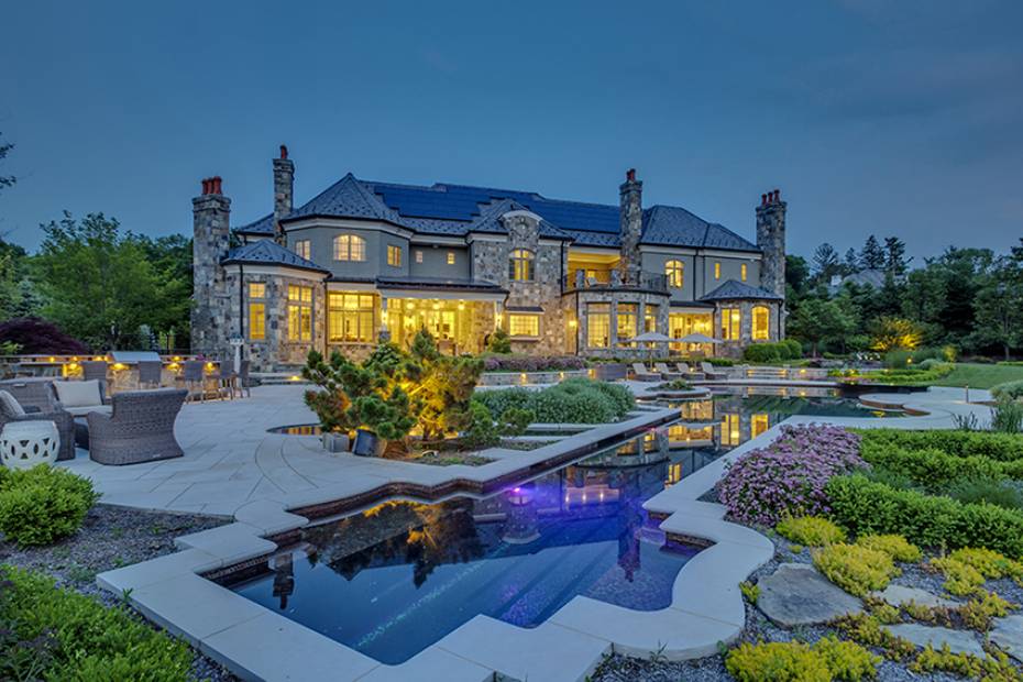 Estate home at dusk with pool and refined outdoor living